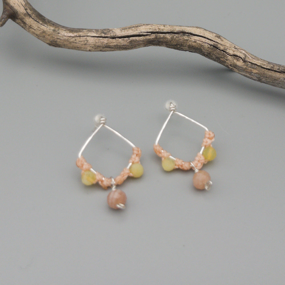 handmade sterling silver, peach moonstone, and yellow opal macrame earrings on a gray background