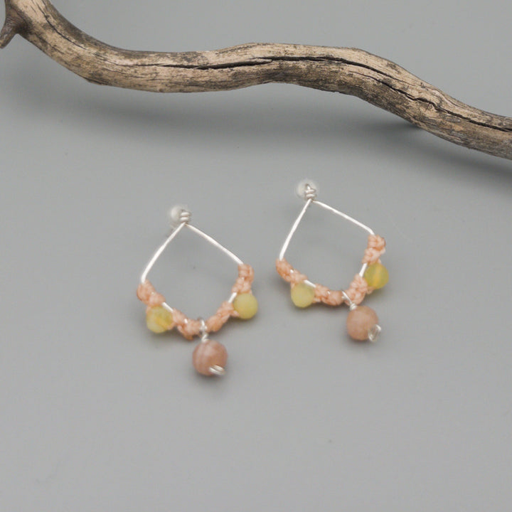 handmade sterling silver, peach moonstone, and yellow opal macrame earrings on a gray background