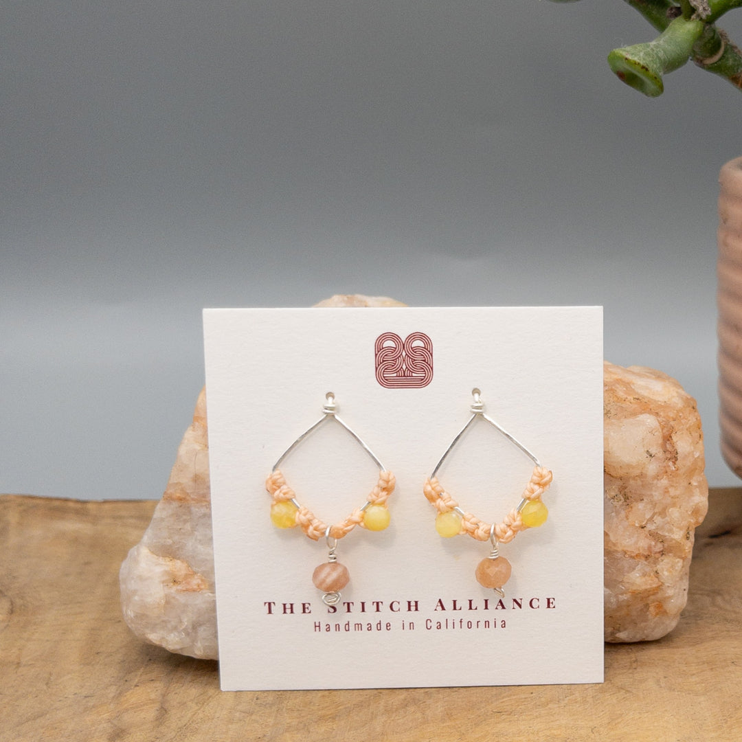handmade sterling silver, peach moonstone, and yellow opal macrame earrings on a white card