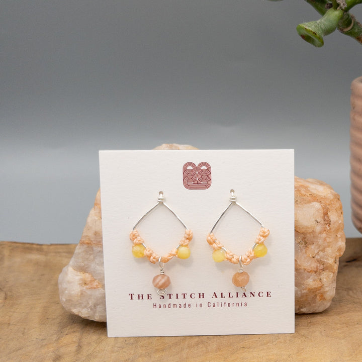 handmade sterling silver, peach moonstone, and yellow opal macrame earrings on a white card