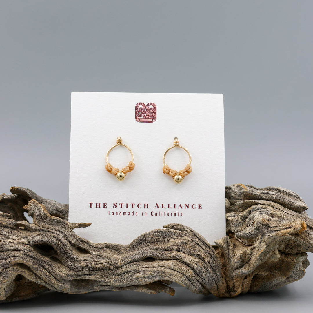 handmade gold macrame stud earrings on a white card