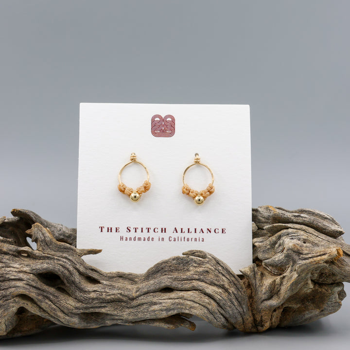 handmade gold macrame stud earrings on a white card