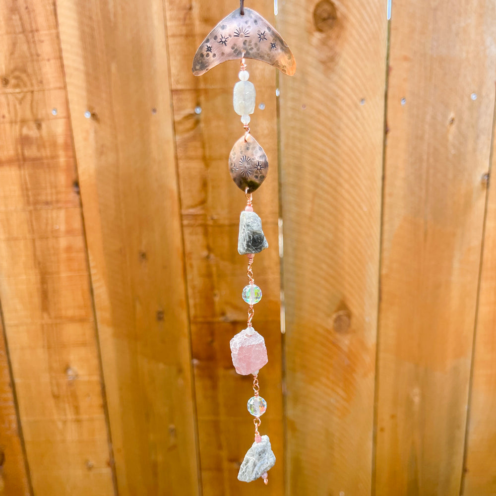 copper, labradorite, and strawberry quartz sun catcher against wood fence