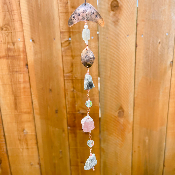 copper, labradorite, and strawberry quartz sun catcher against wood fence