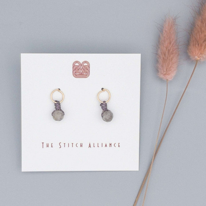 14k gold filled circle post earrings with a labradorite bead on a gray background