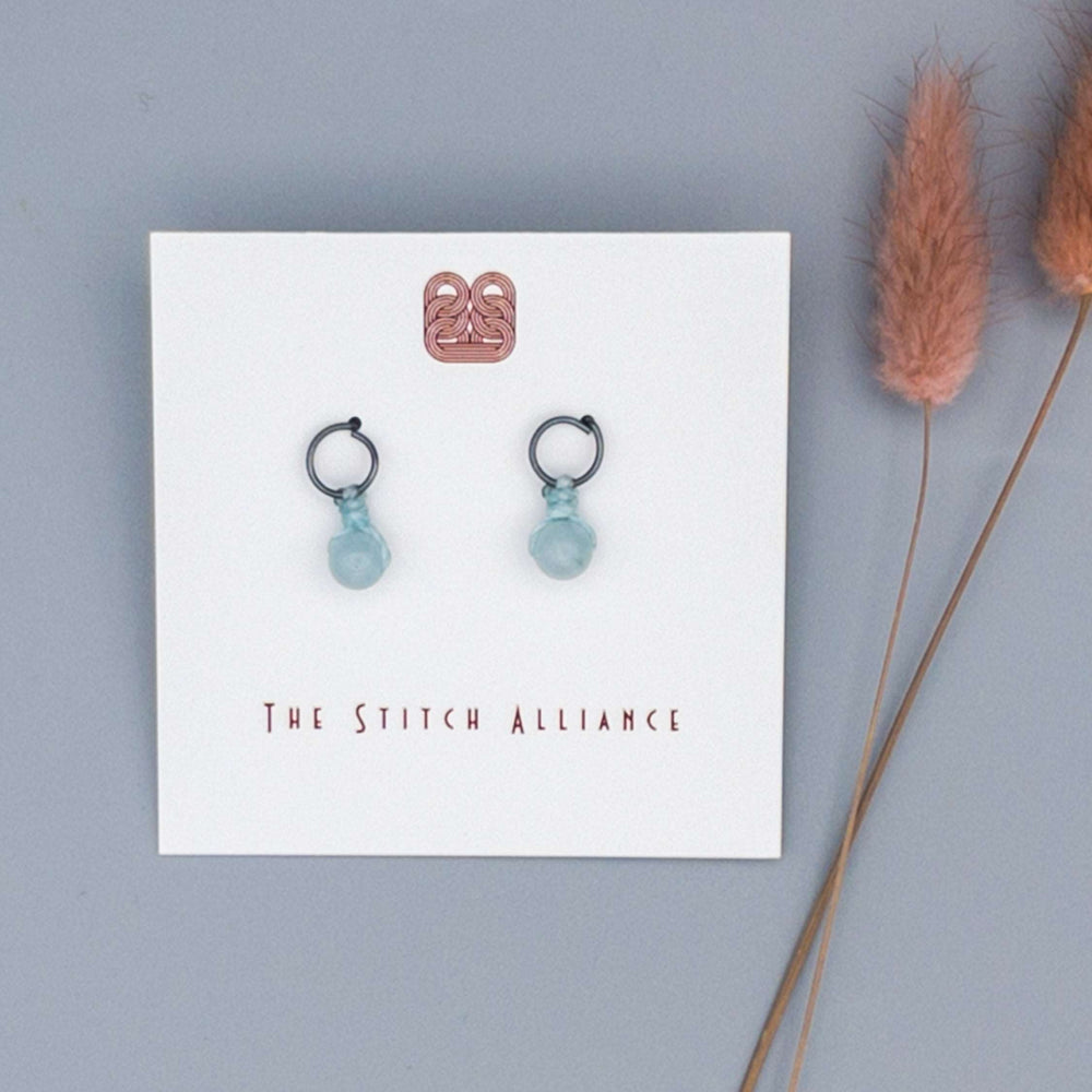 oxidized sterling silver post-style earrings with an aquamarine bead on a gray background
