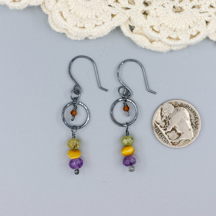 handmade oxidized sterling silver, amethyst, golden tigers eye, green garnet, and hessonite dangle earrings with a nickel for size comparison