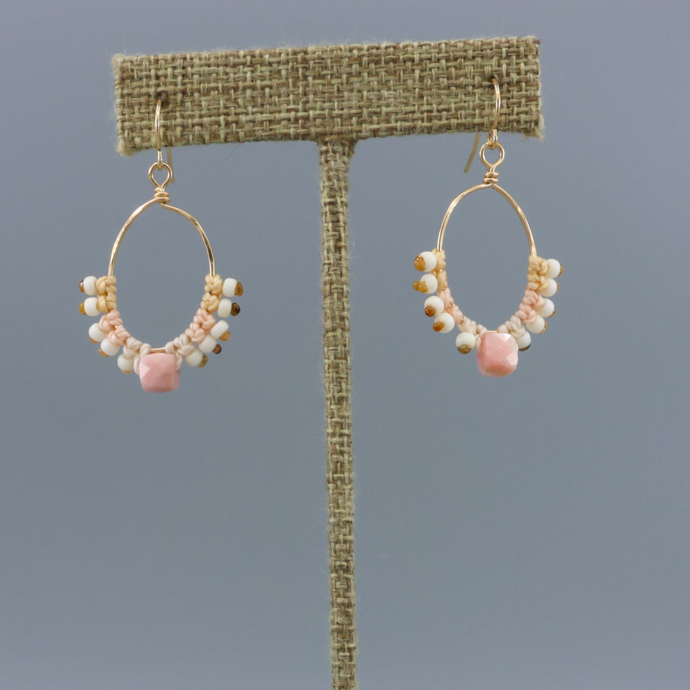 handmade gold macrame hoop earrings with a pink opal bead on a linen display hanger