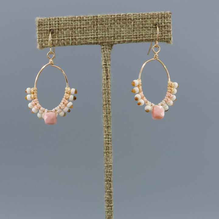 handmade gold macrame hoop earrings with a pink opal bead on a linen display hanger