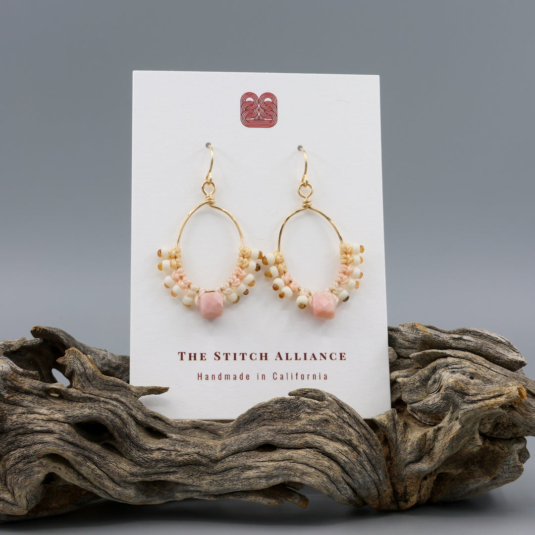 handmade gold macrame hoop earrings with a pink opal bead on a white card