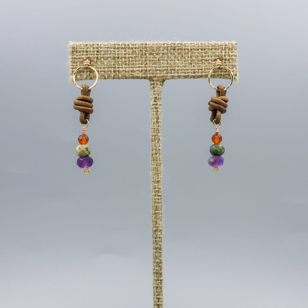 handmade amethyst, green garnet, and hessonite leather and gold fill earrings on a linen hanger