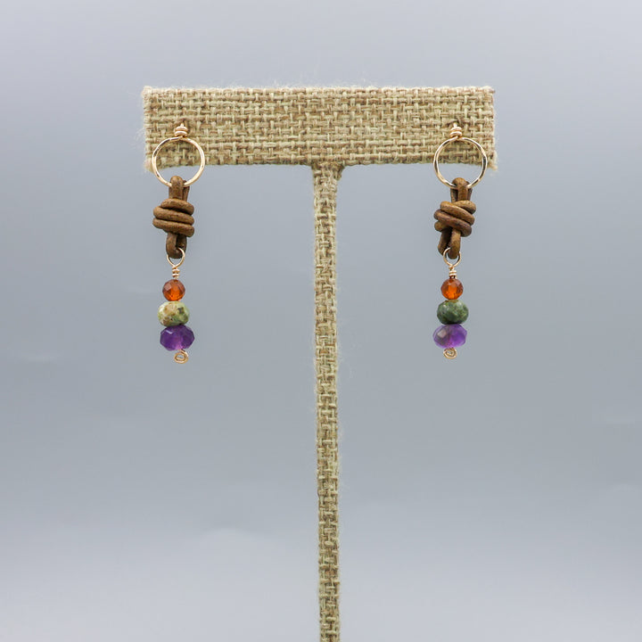 handmade amethyst, green garnet, and hessonite leather and gold fill earrings on a linen hanger