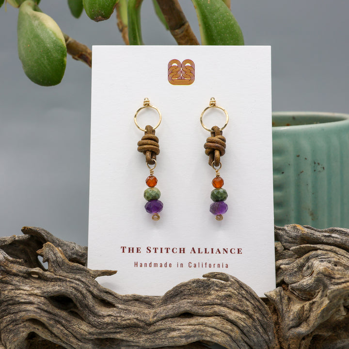 handmade amethyst, green garnet, and hessonite leather and gold fill earrings on a white display card
