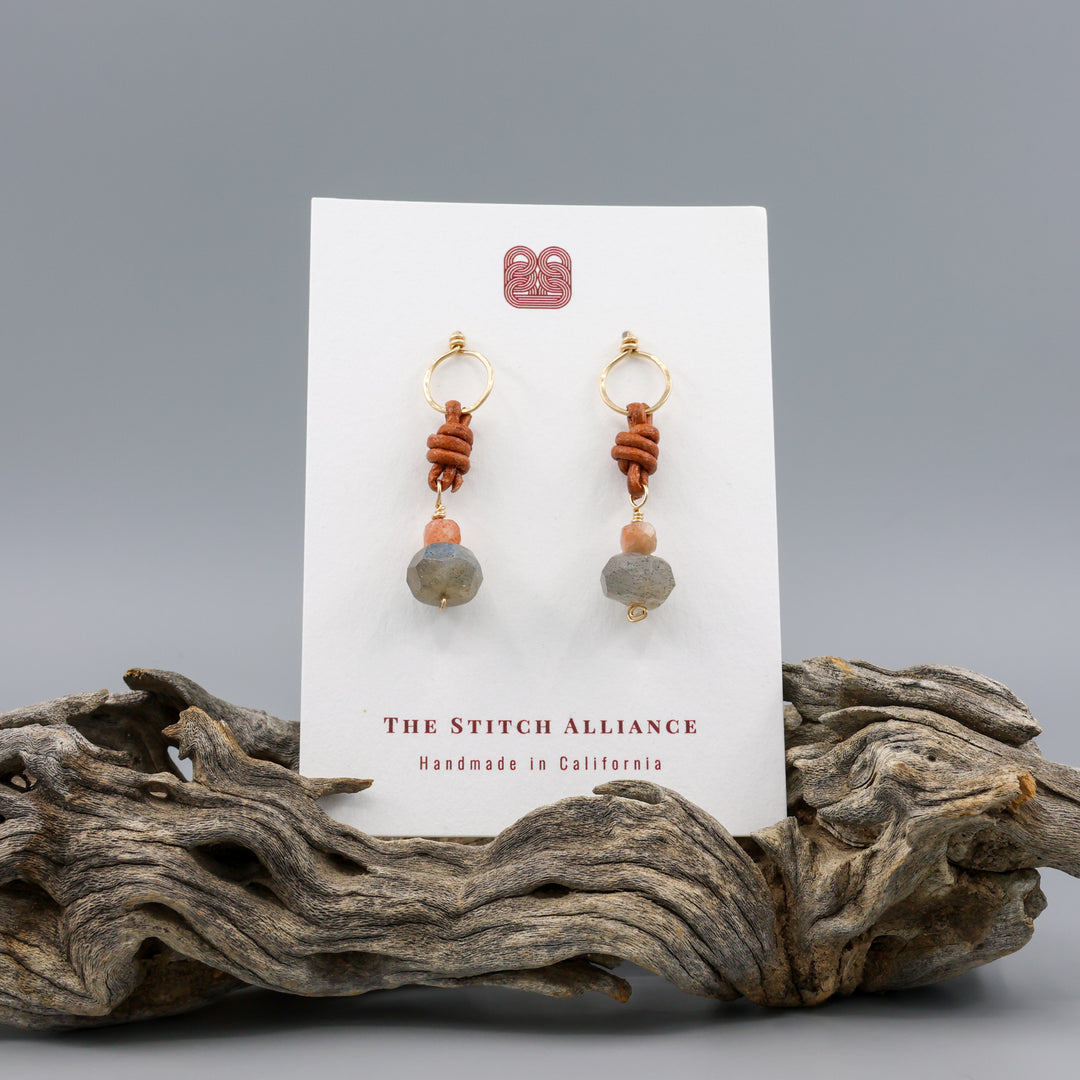 labradorite, sunstone, gold fill, and leather handmade drop earrings on a white card