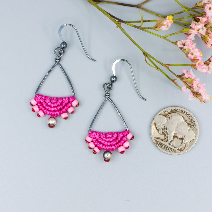 handmade oxidized sterling silver triangle hoop earrings with bright pink macrame with a nickel for size comparison