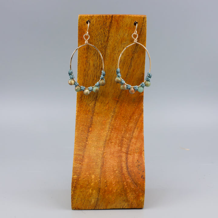 handmade gold hoop macrame earrings with aqua terra jasper beads on a wood display