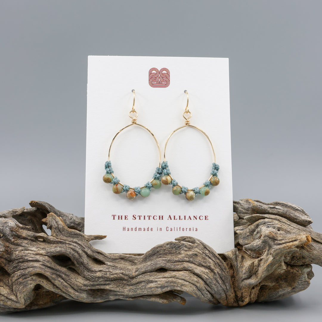 handmade gold hoop macrame earrings with aqua terra jasper beads on a white card