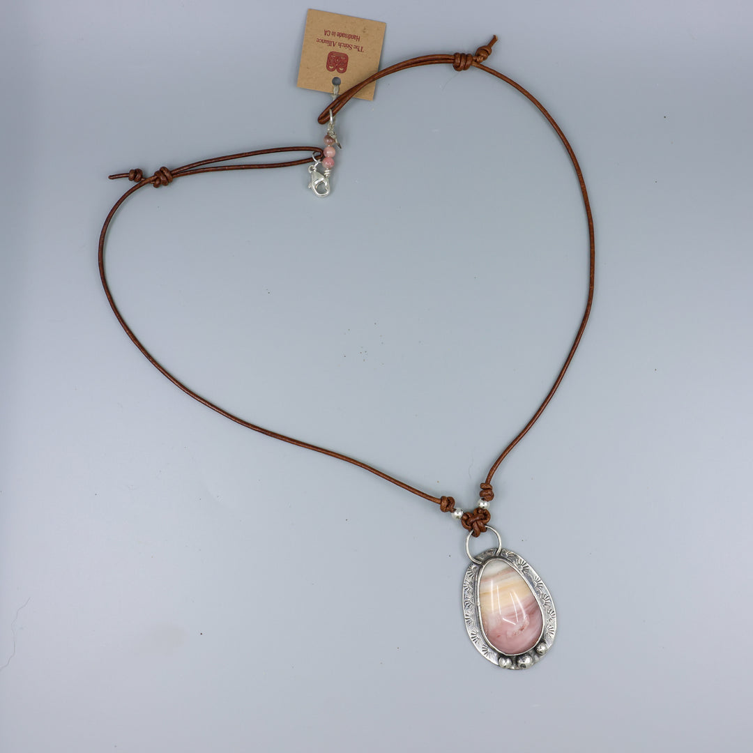 pink and yellow jasper sterling silver necklace on leather cord on a gray background