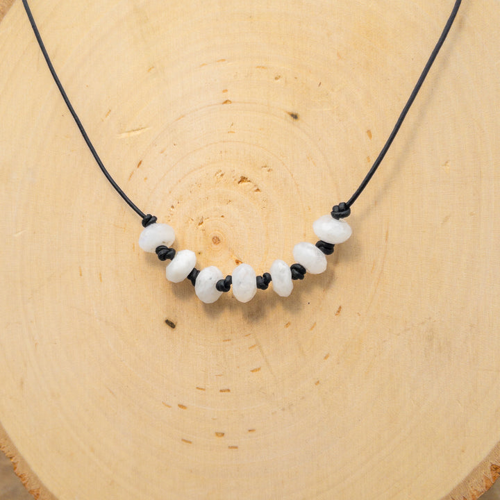 hand knotted rainbow moonstone beaded necklace on black leather with sterling silver clasp on wood background