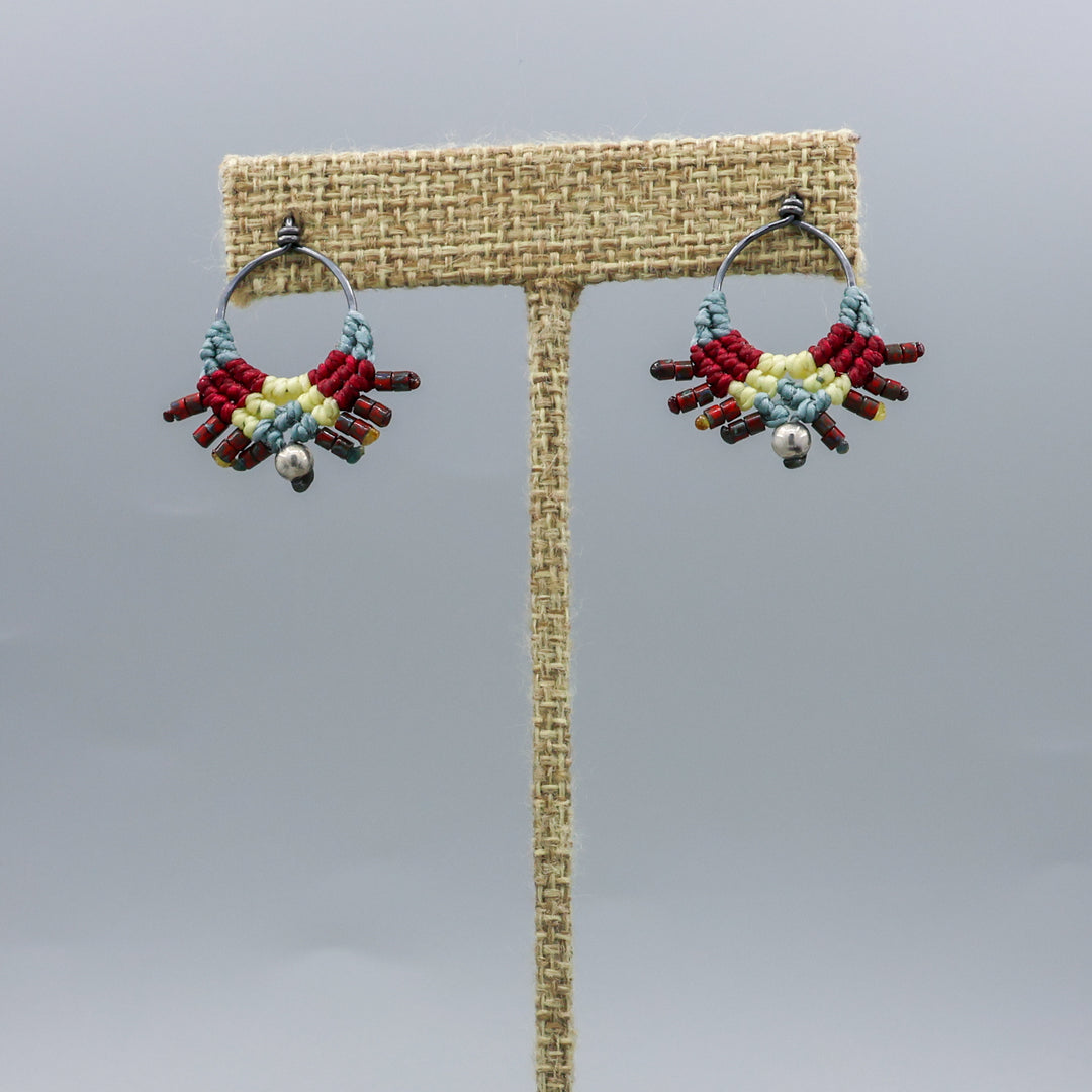 handmade macrame stud earrings in blue, deep red, and pale yellow with oxidized sterling silver metal on a linen hanger