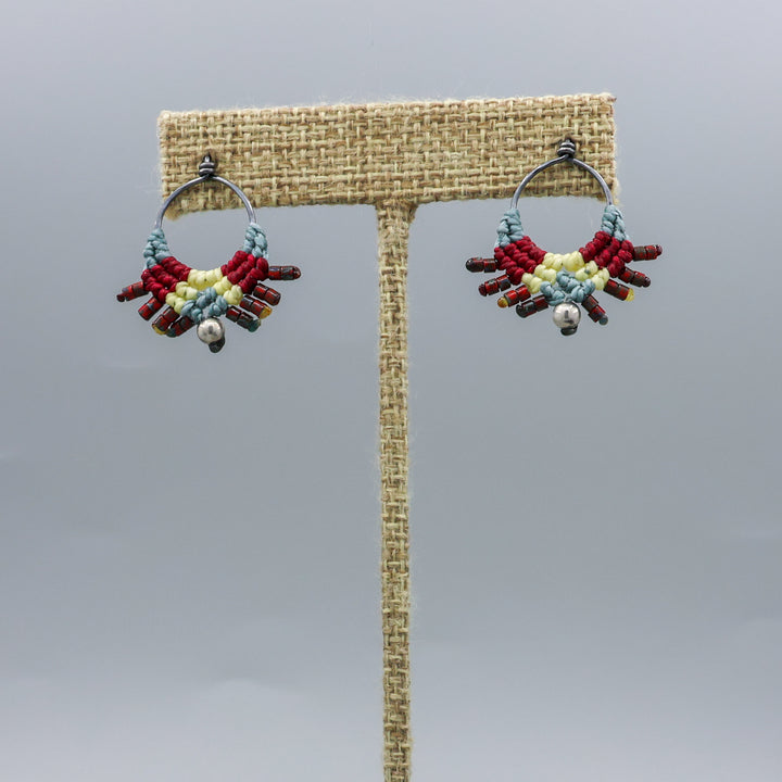 handmade macrame stud earrings in blue, deep red, and pale yellow with oxidized sterling silver metal on a linen hanger