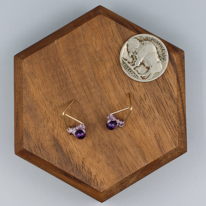handmade gold fill amethyst triangle stud earrings with a nickel for size comparison