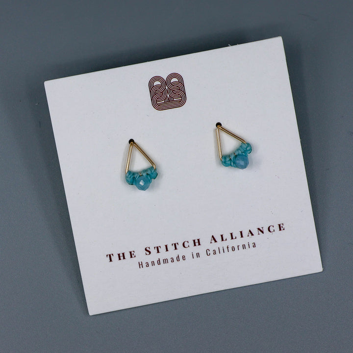 handmade gold filled triangle stud earrings with aquamarine beads on a white card and gray background