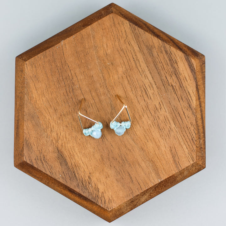 handmade gold filled triangle stud earrings with aquamarine beads on a wood display