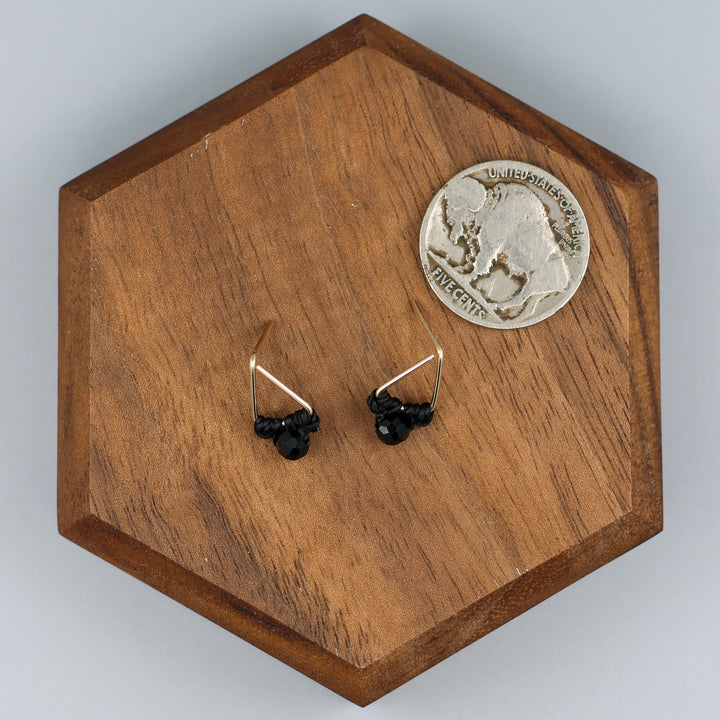 handmade triangle shaped earrings in gold fill with a black spinel bead with a nickel for size comparison