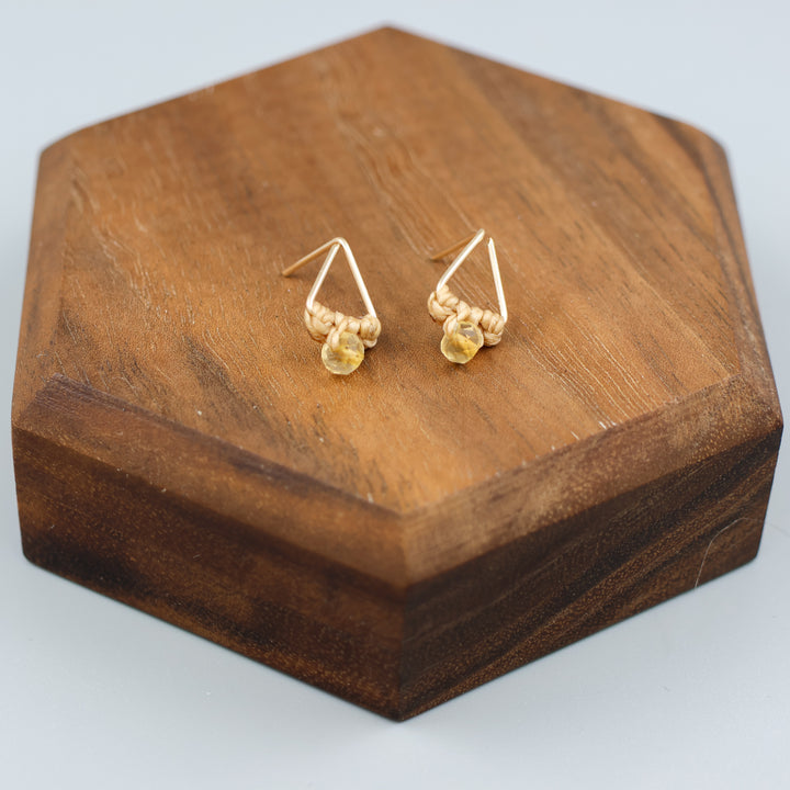 handmade gold fill  triangle stud earrings with a citrine bead on a wood display