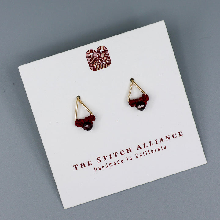 handmade gold filled triangle stud earrings with garnet beads on a white card with gray background