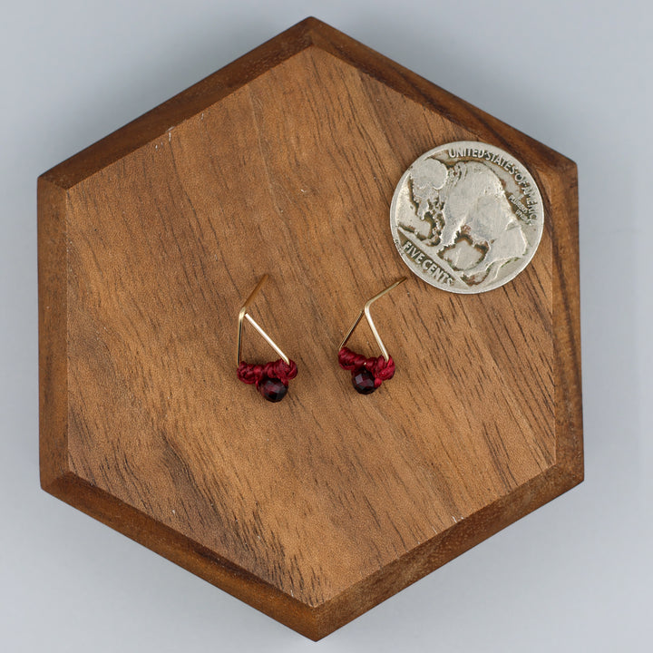 handmade gold filled triangle stud earrings with garnet beads with a nickel for size comparison
