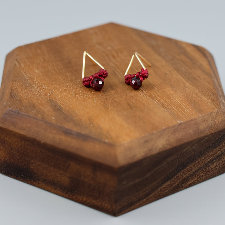 handmade gold filled triangle stud earrings with garnet beads on wood display