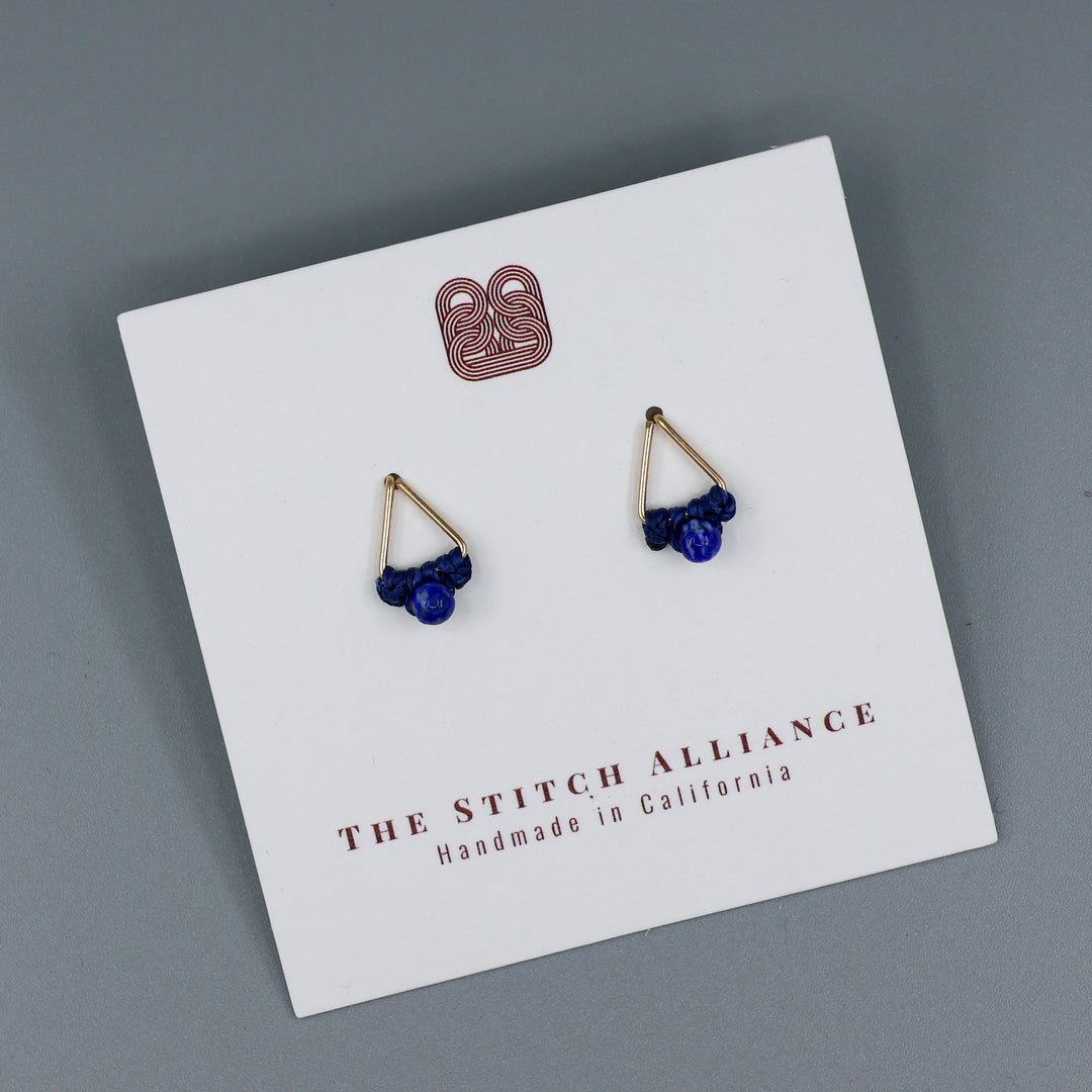 handmade triangle shaped earrings in gold fill with a lapis lazuli bead on a white card and gray background