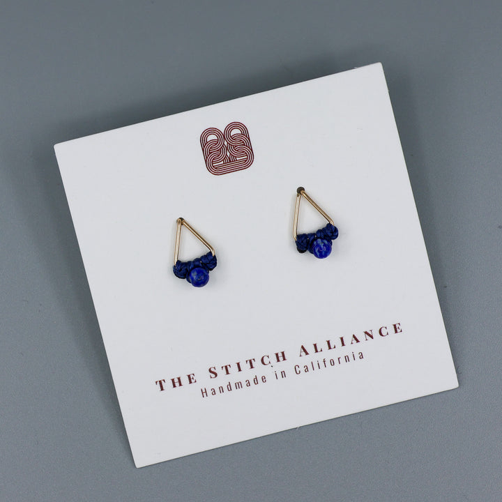 handmade triangle shaped earrings in gold fill with a lapis lazuli bead on a white card and gray background