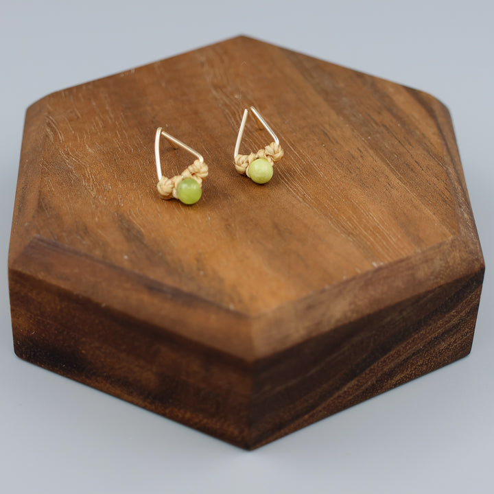 handmade gold fill  triangle stud earrings with peridot beads on a wood display