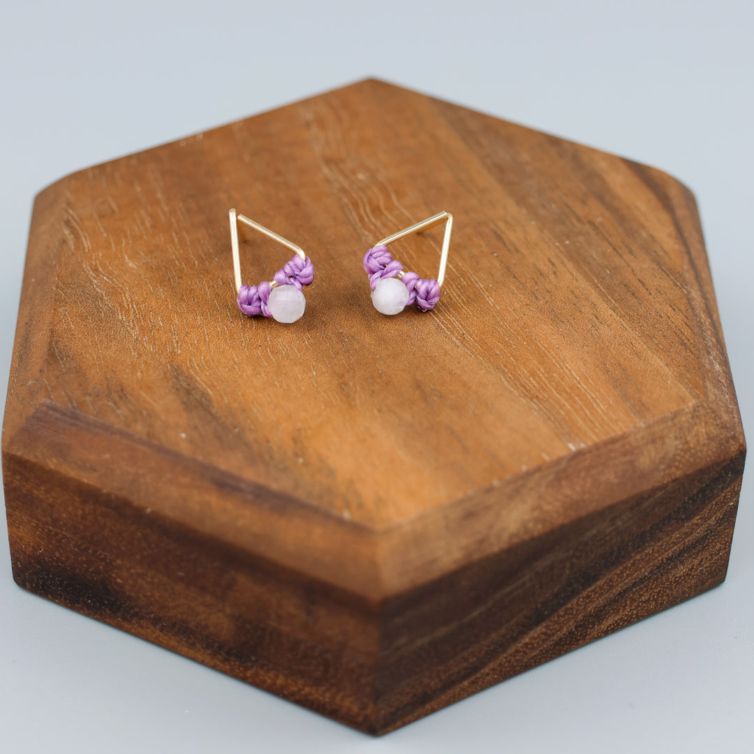 handmade triangle shaped earrings in gold fill with a rainbow moonstone bead on a wood display