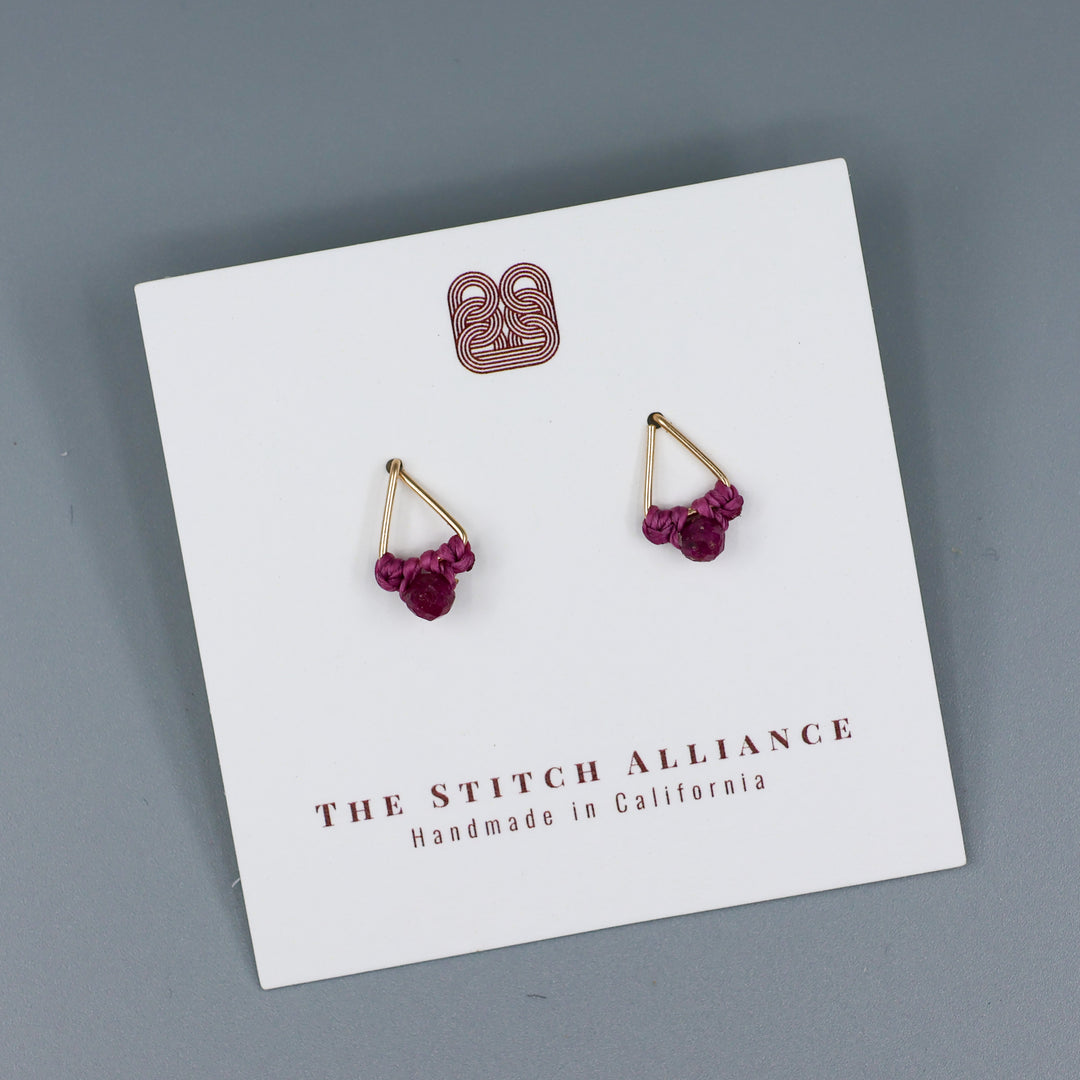 handmade gold filled triangle stud earrings with ruby beads  on a white card with a gray background