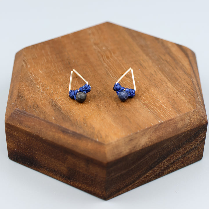 handmade gold filled triangle stud earrings with sapphire beads on a wood display