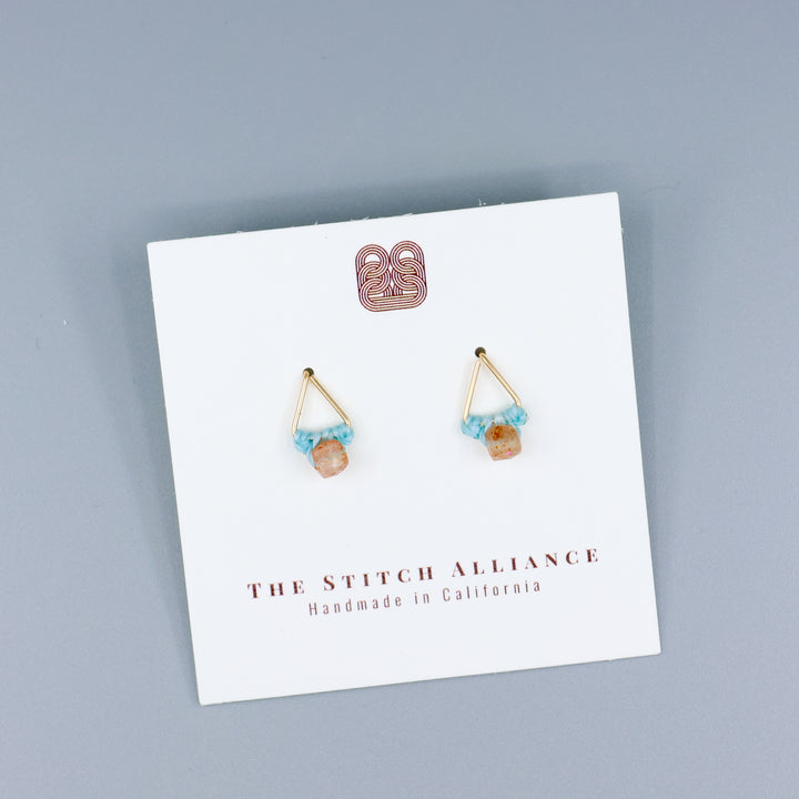 handmade triangle shaped earrings in gold fill with a sunstone bead on a white card with gray background