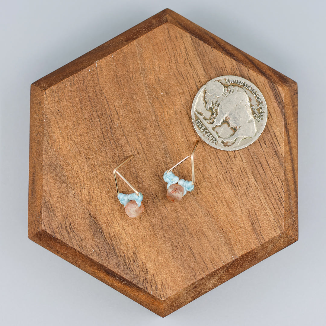 handmade triangle shaped earrings in gold fill with a sunstone bead with a nickel for size comparison