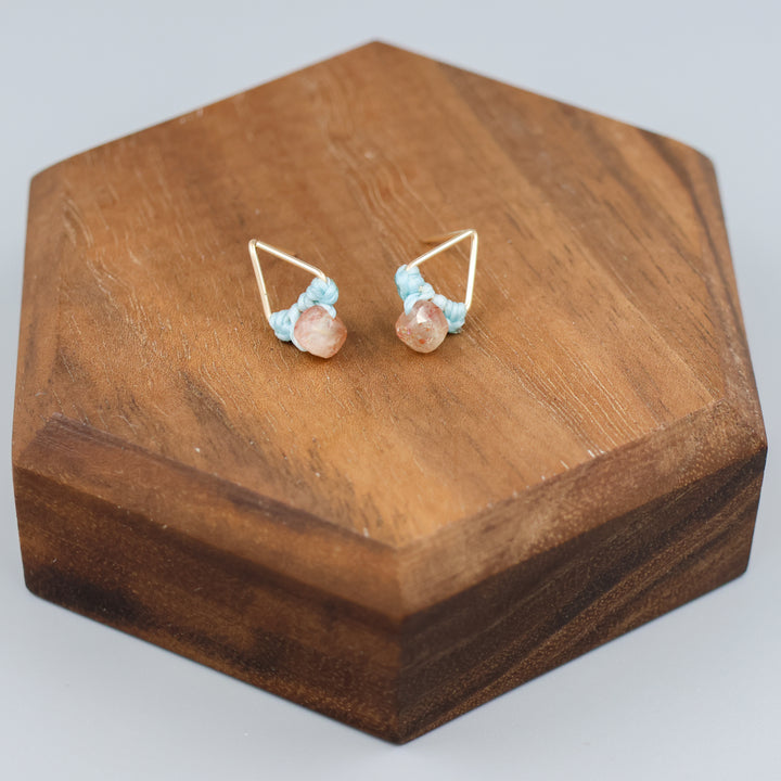 handmade triangle shaped earrings in gold fill with a sunstone bead on wood display