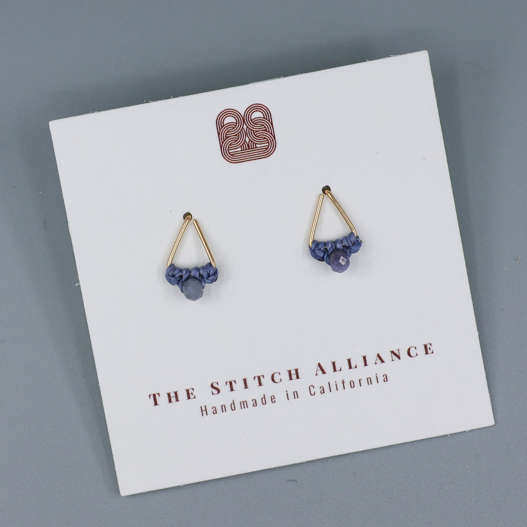handmade gold filled triangle stud earrings with tanzanite beads on a white card with a gray background