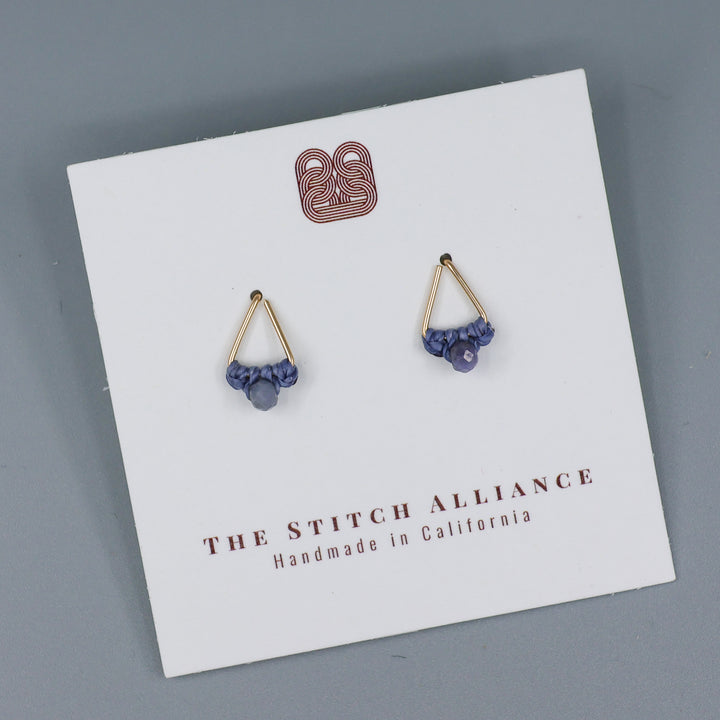 handmade gold filled triangle stud earrings with tanzanite beads on a white card with a gray background