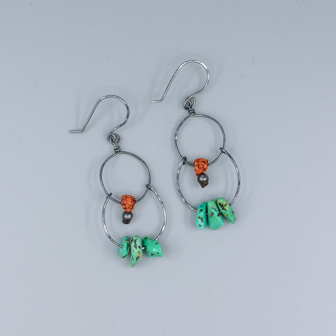handmade double hoop earrings with turquoise beads and oxidized sterling silver on a gray background