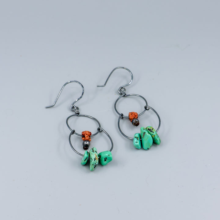 handmade double hoop earrings with turquoise beads and oxidized sterling silver on a wood display detail view
