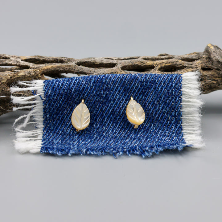 Mother of Pearl gold stud earrings shown on denim