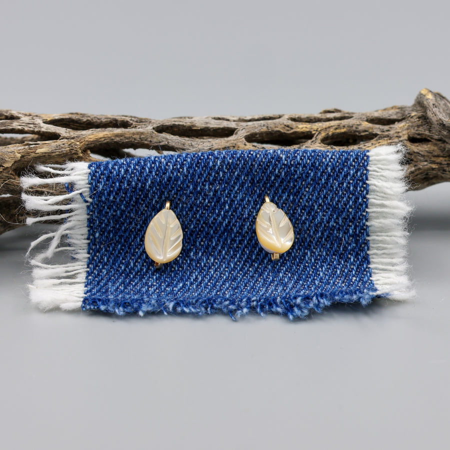 Mother of Pearl gold stud earrings shown on denim