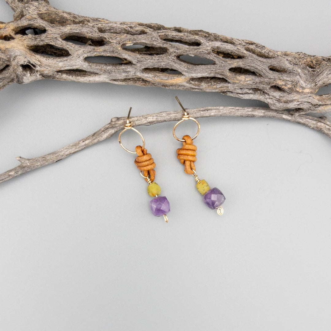 sundance earrings amethyst and jade gold filled earrings with leather knotting on a gray background