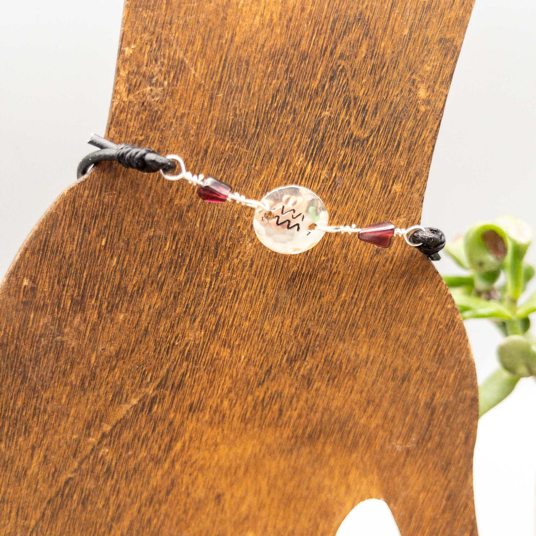 Aquarius bracelet with garnet beads and hand-stamped Aquarius symbol on sterling silver